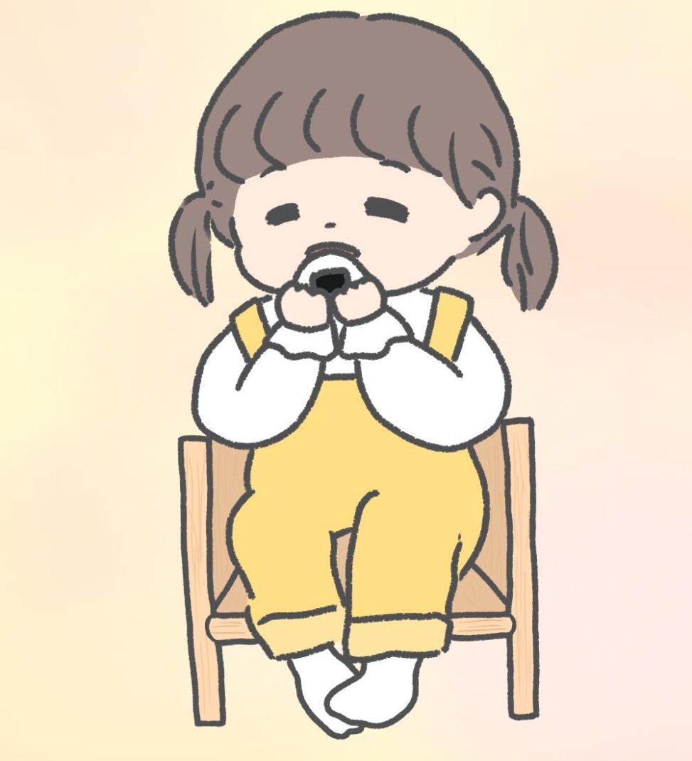 幼児用の木の椅子に座っておにぎりを食べている女の子